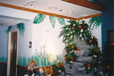 Mural featuring large rock with flowers and dolls